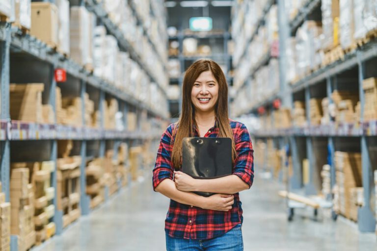 Portrait of Asian woman warehouse worker standing and holding the clipboard